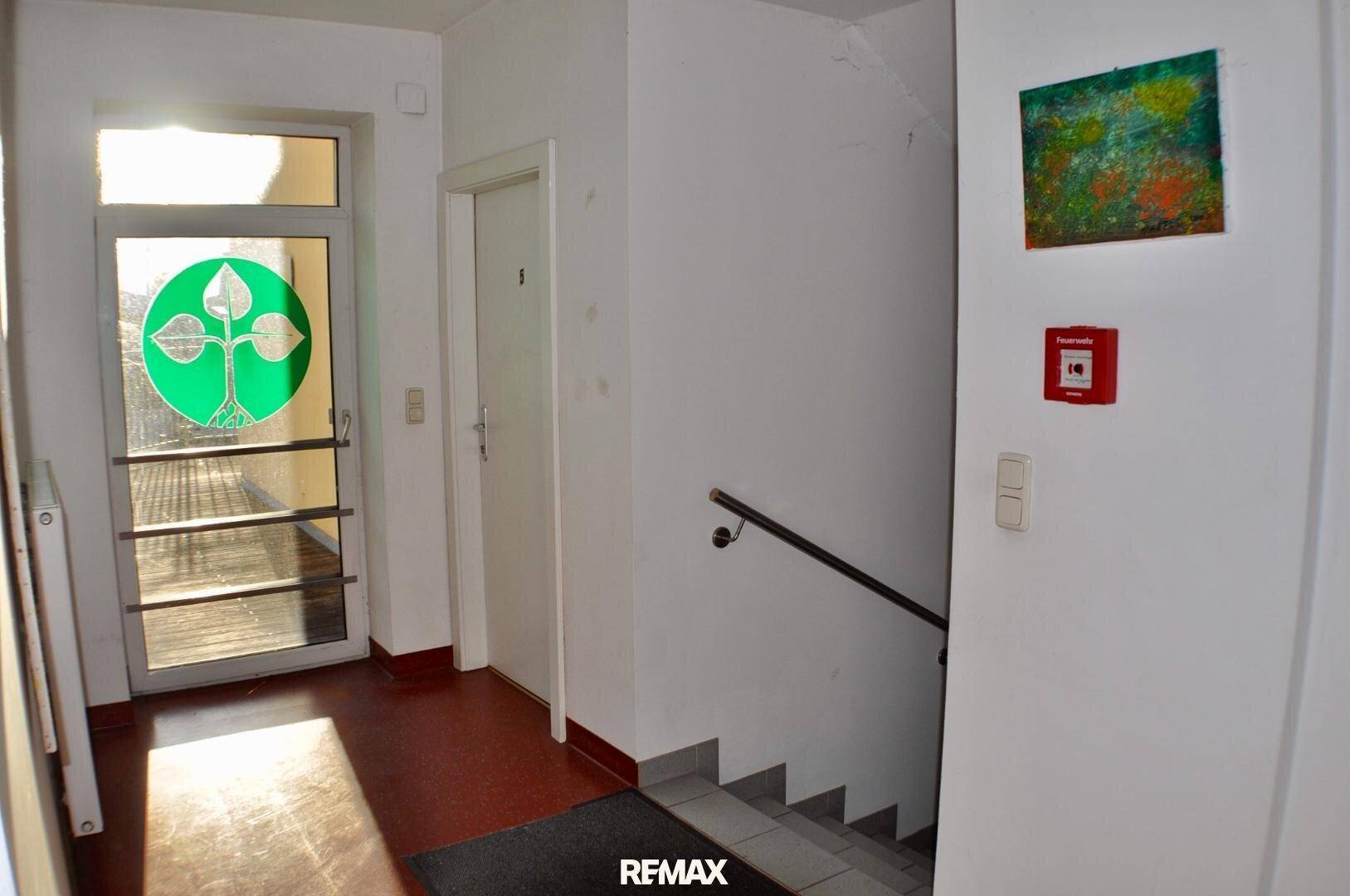 Eingangsbereich mit Treppe, Fliesenboden und einer Tür mit dekorativem Glaseinsatz, hell und einladend.