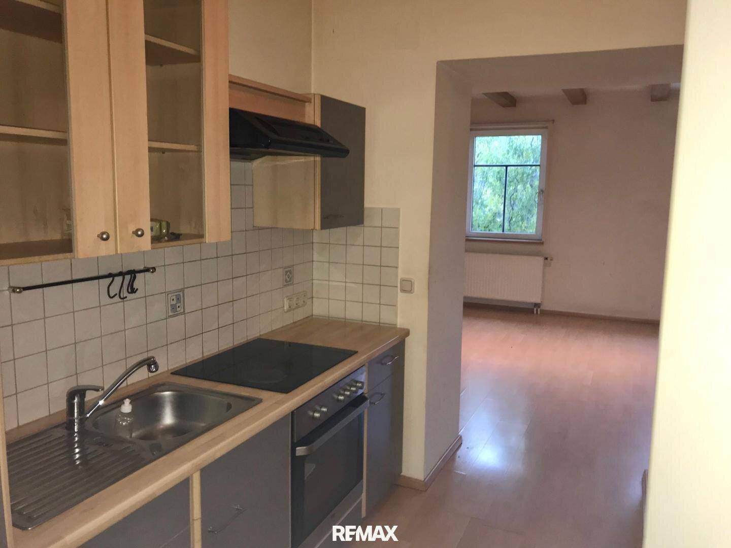 Küchenzeile mit Spüle, Kochfeld und Backofen, gefliestem Spritzschutz und Holztheke, funktional und kompakt.