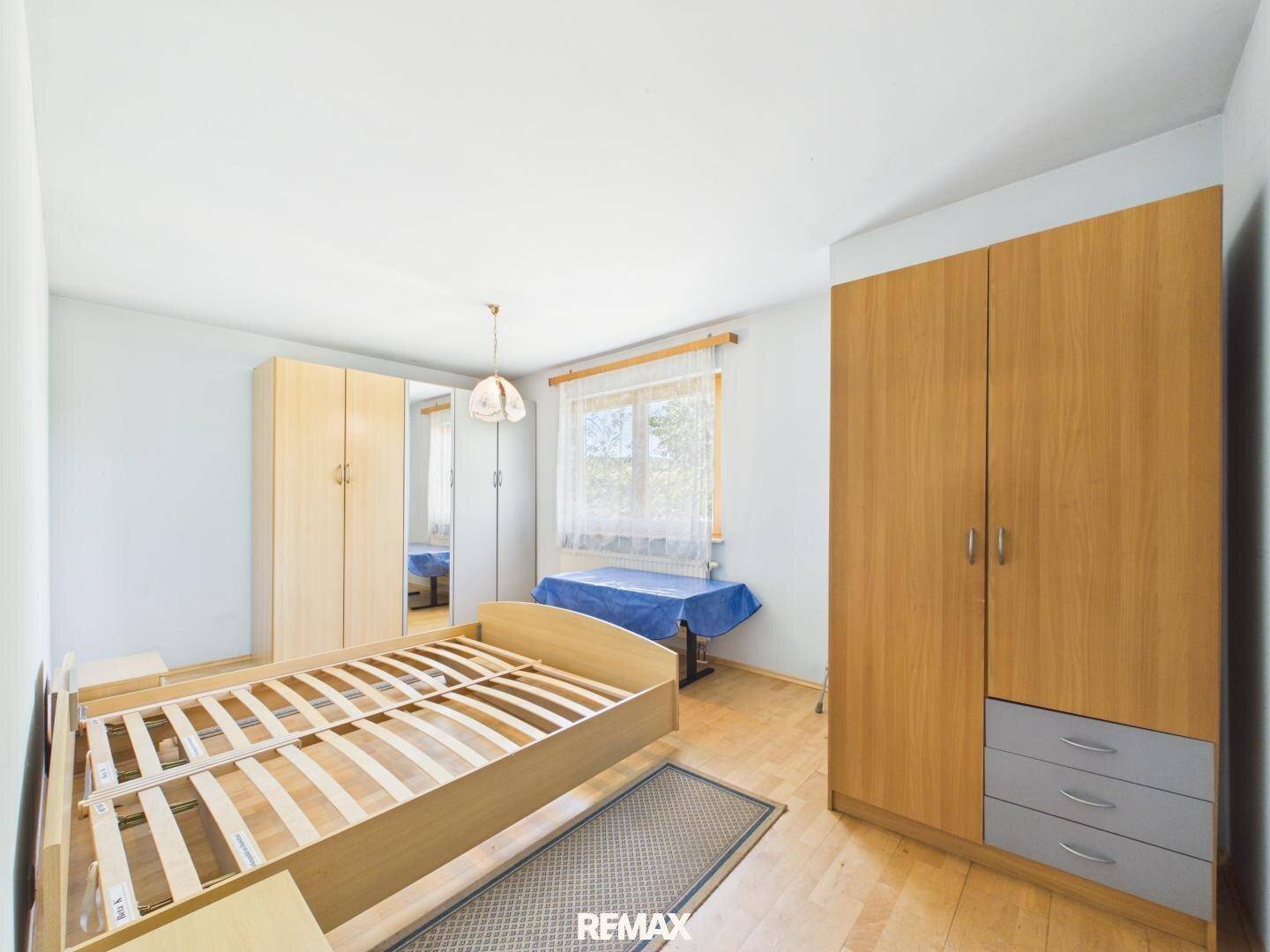 Schlafzimmer mit Holzboden, Bettrahmen und Kleiderschränken, hell und funktional eingerichtet.