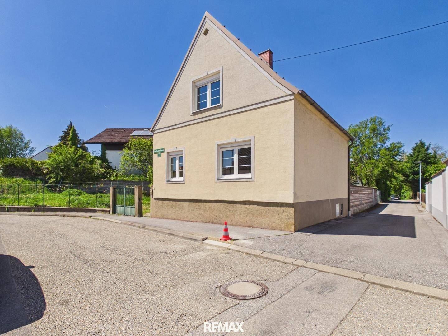 Ansicht des Hauses von der Straße mit Giebeldach und gepflegter Fassade unter blauem Himmel.