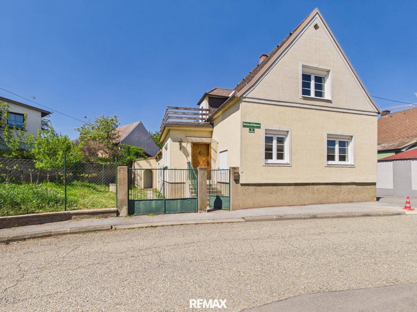 Vorderansicht des Hauses von der Straße aus mit einem Giebeldach und weiß gestrichenen Fenstern.