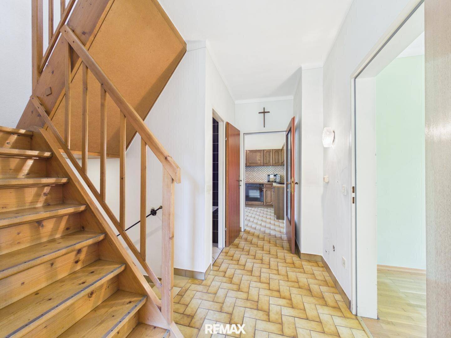 Flur mit Holztreppe und Terrakottafliesen, der zu weiteren Räumen und in die obere Etage führt.