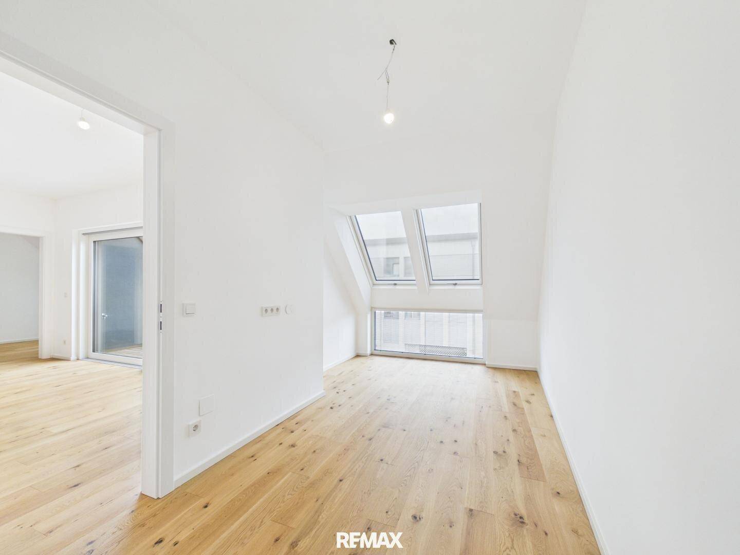 Helles Zimmer mit Holzboden und großen Dachfenstern, ideal als Schlafzimmer.