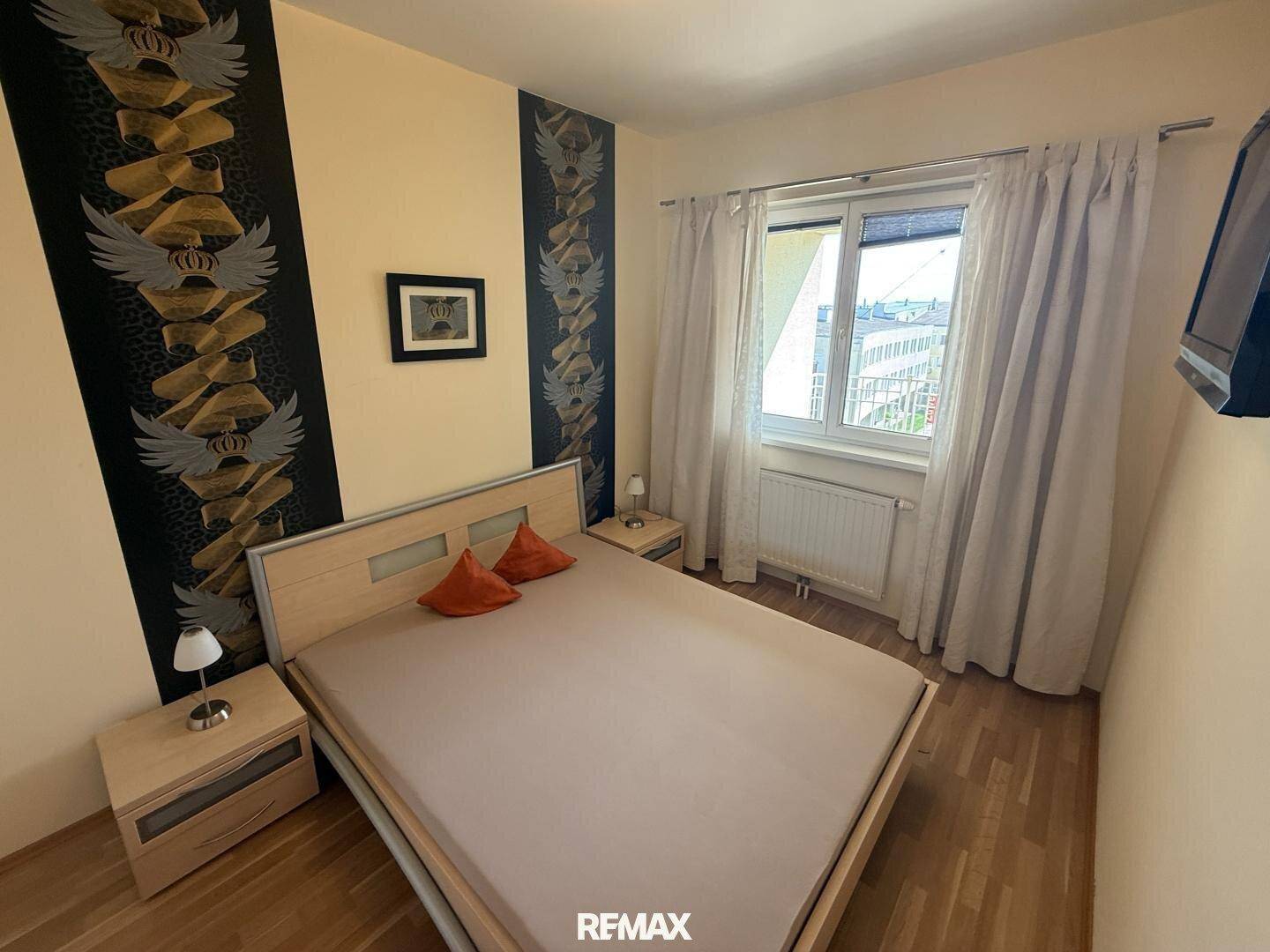 Schlafzimmer mit Doppelbett, Nachttischen und Fenster mit Vorhängen.