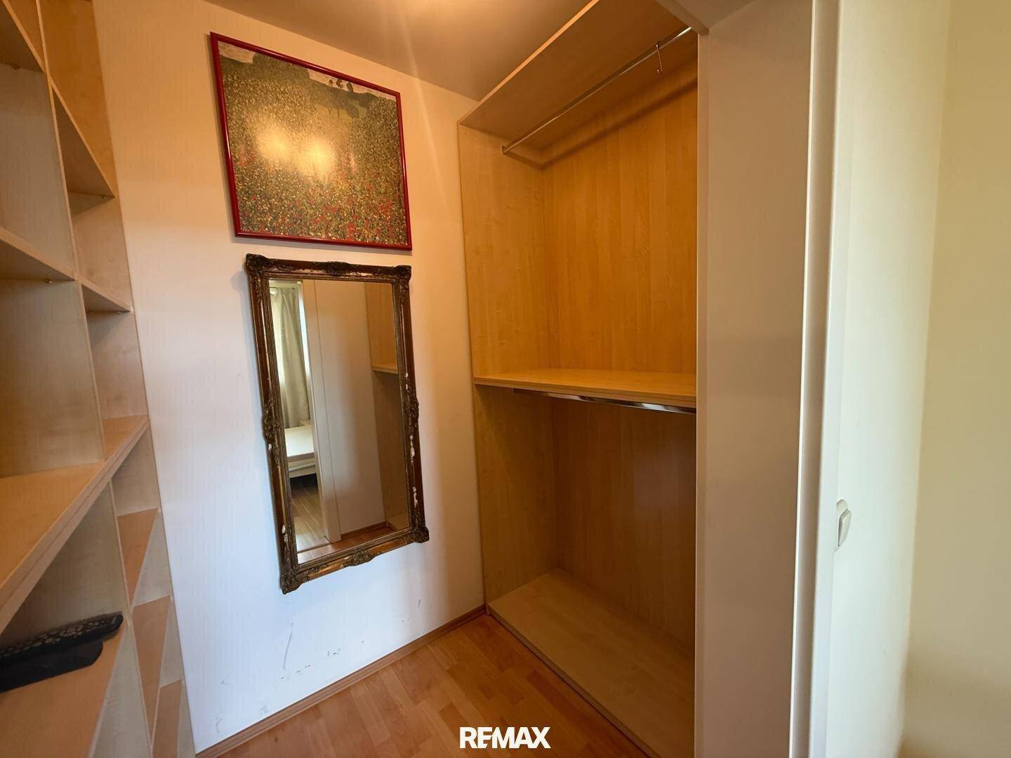 Begehbarer Kleiderschrank mit Regalen und Spiegel, ideal für zusätzlichen Stauraum.