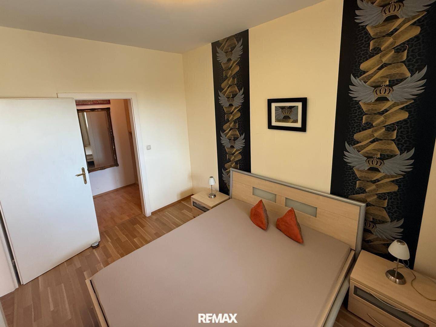 Schlafzimmer mit Bett und Zugang zu einem weiteren Raum, möglicherweise einem Ankleidezimmer.