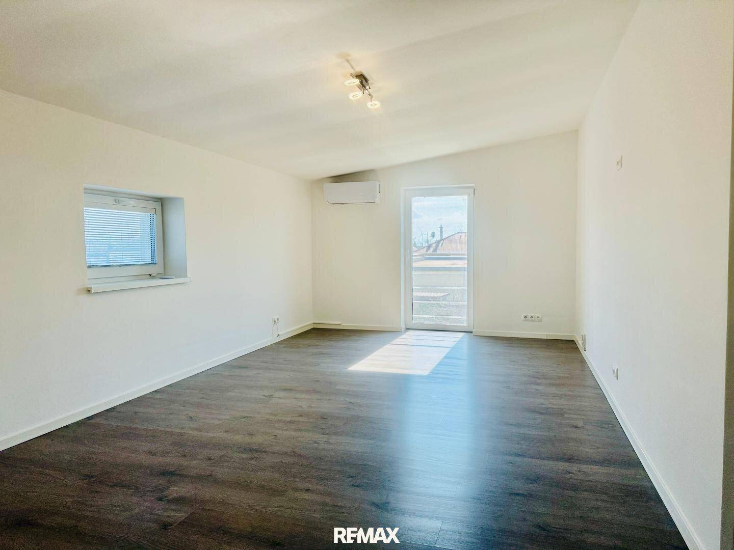 Helles Schlafzimmer im Dachgeschoss mit Laminatboden und Zugang zu einem Balkon.