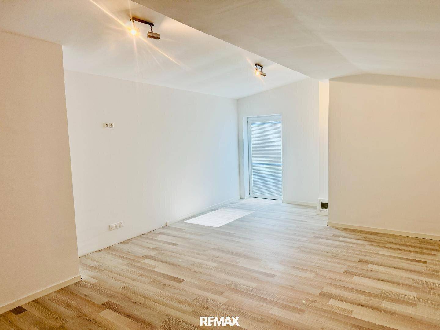 Geräumiger, heller Raum mit Laminatboden und Zugang zu einem Balkon oder einer Terrasse.