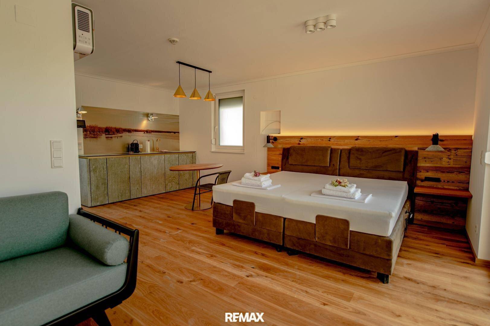 Gemütliches Schlafzimmer mit Doppelbett, integrierter Küchenzeile und Holzboden.