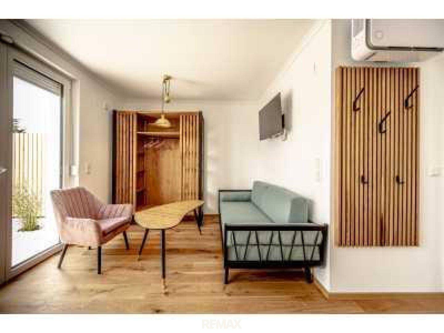 Moderner Wohnbereich mit bequemen Sitzgelegenheiten, Holzmöbeln und Zugang zur Terrasse.