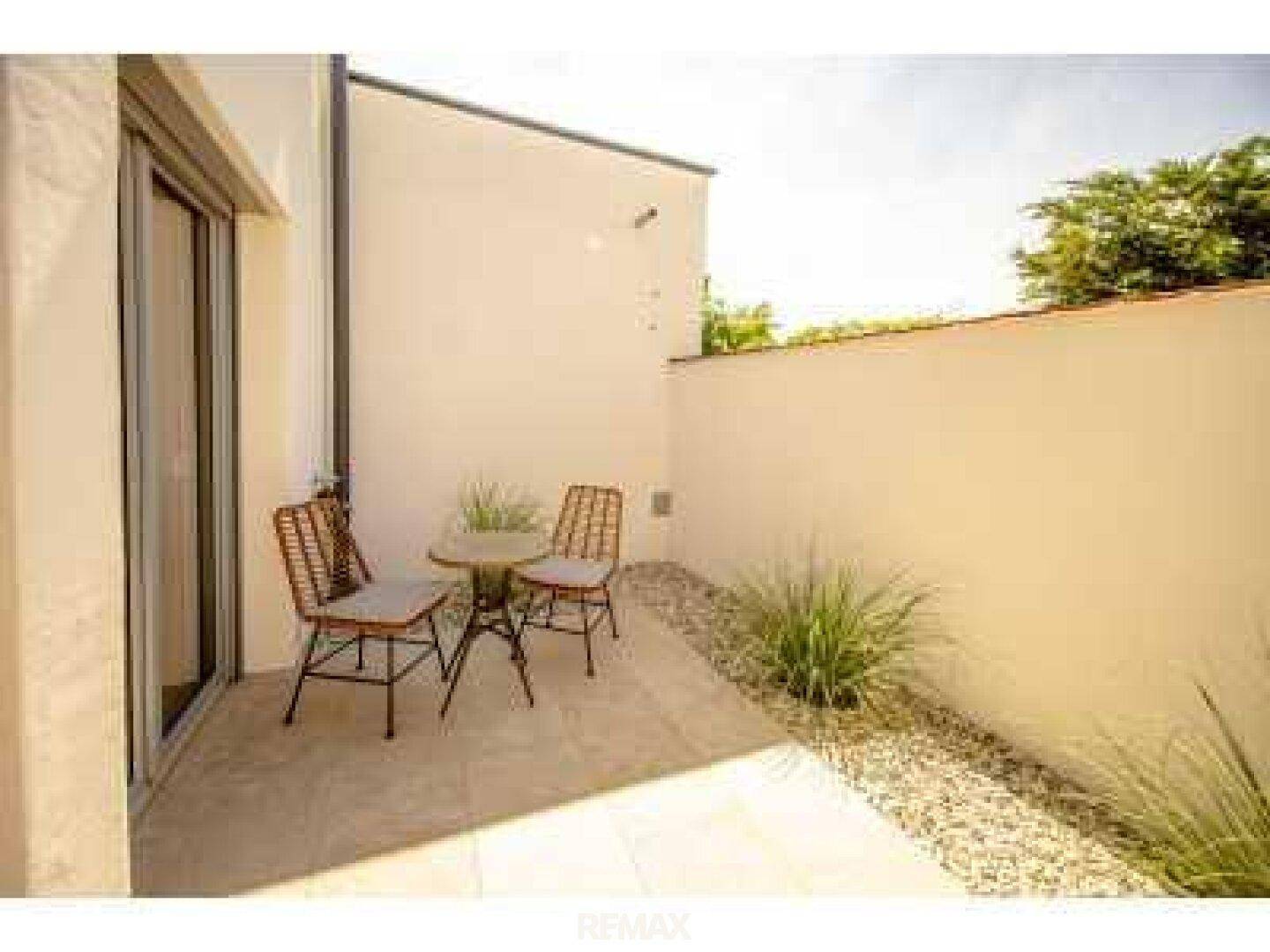 Kleine, private Terrasse mit Sitzgelegenheiten, umgeben von Mauern und Pflanzen.