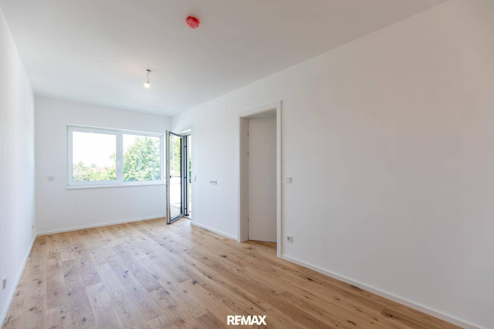 Geräumiges Zimmer mit Holzboden und Fenster, das viel Tageslicht hereinlässt.