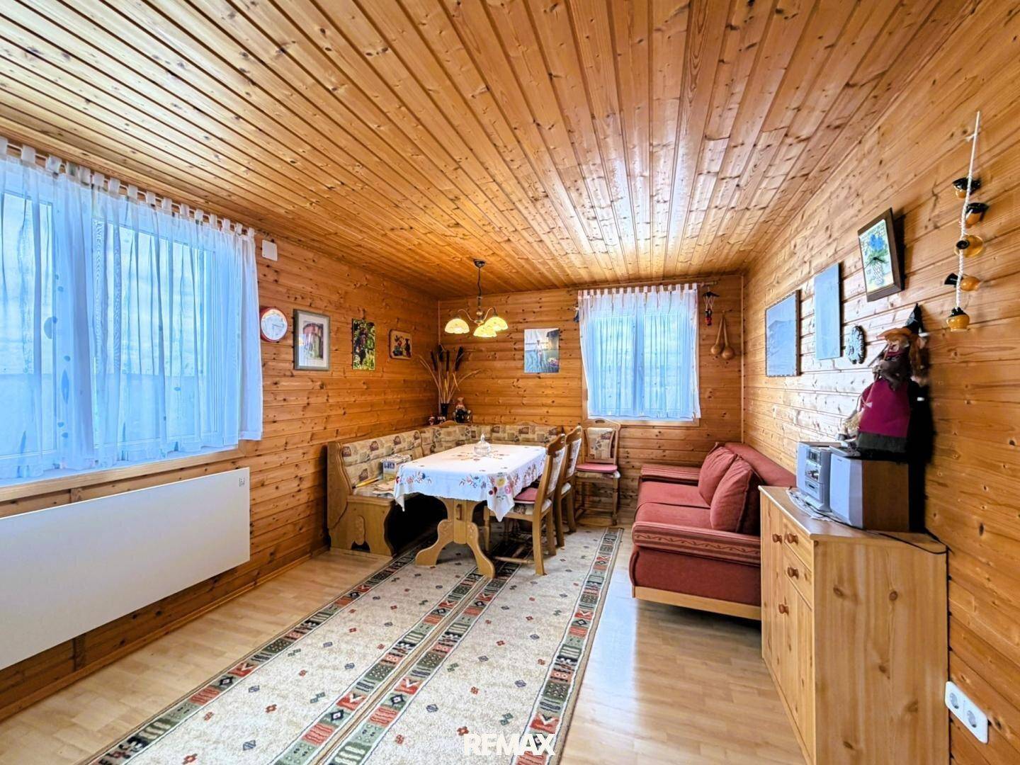 Geräumiger Essbereich mit Eckbank und Holztisch, umgeben von Holzwänden und -decke, mit Teppichboden.