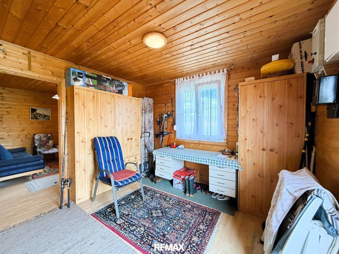 Gemütliches Zimmer mit Holzvertäfelung, Schreibtisch und Stauraum, ideal als Schlaf- oder Arbeitsbereich.