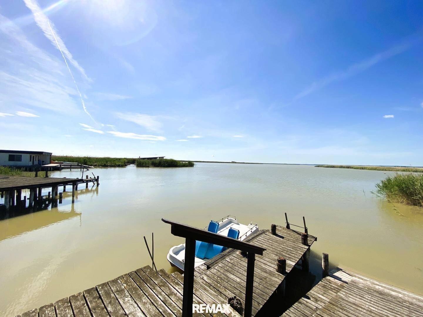 Weitläufige Wasserlandschaft mit Anlegestellen und einem Boot unter strahlend blauem Himmel.