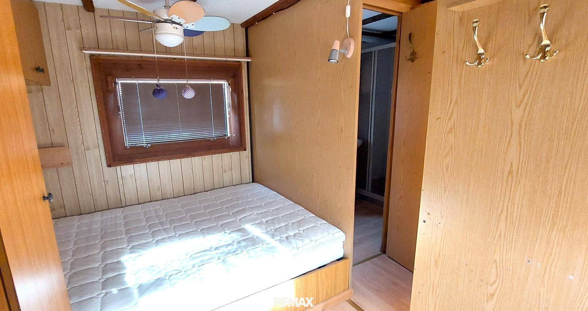 Schlafzimmer mit Bett und Zugang zu einem weiteren Raum, beleuchtet durch ein Fenster.