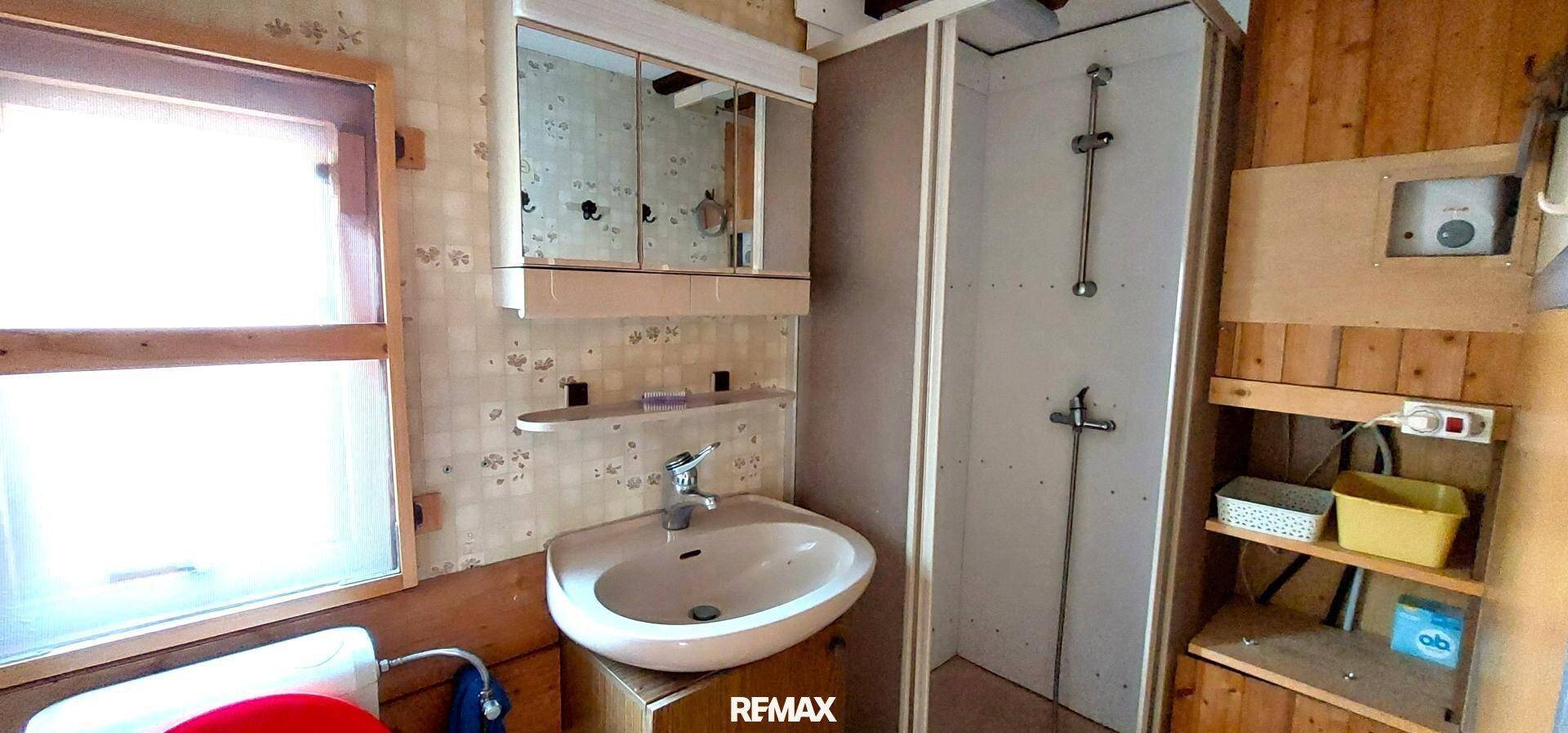 Kleines Badezimmer mit Waschbecken, Spiegelschrank und Duschkabine, funktional eingerichtet.