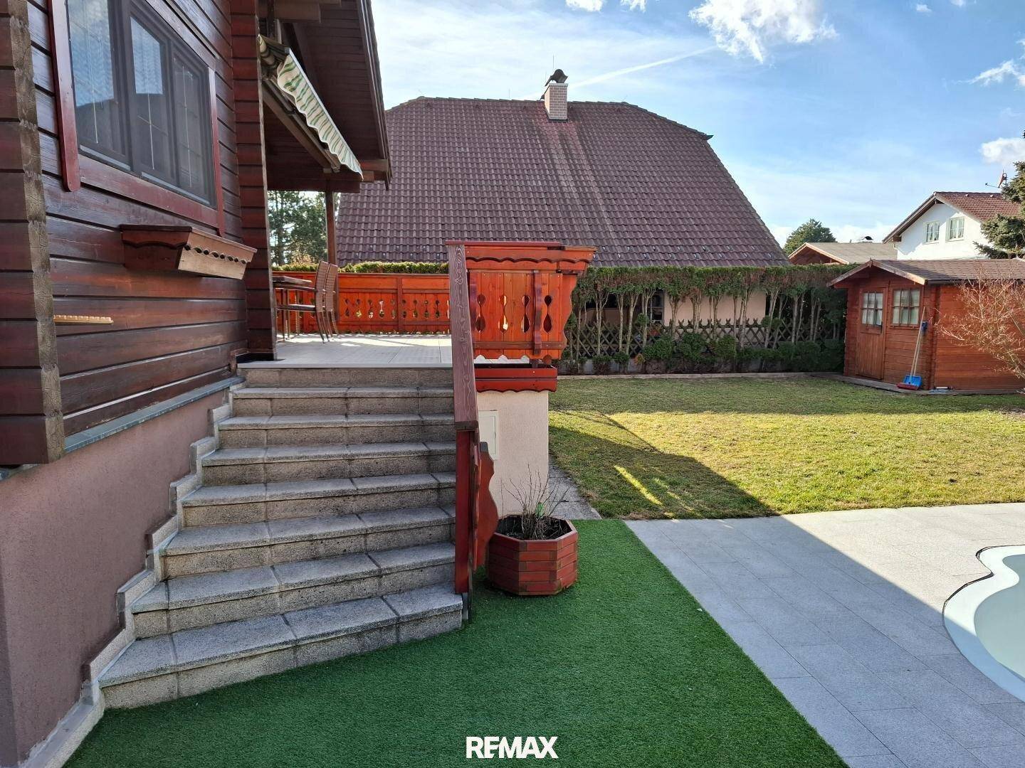 Gepflegter Gartenbereich mit Steintreppe, Rasenfläche und Zugang zum Pool.