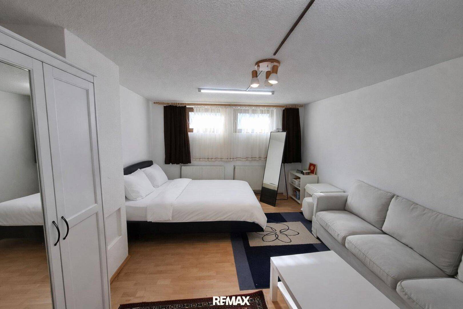 Helles Schlafzimmer im Untergeschoss mit Doppelbett, Sofa und Holzfußboden.