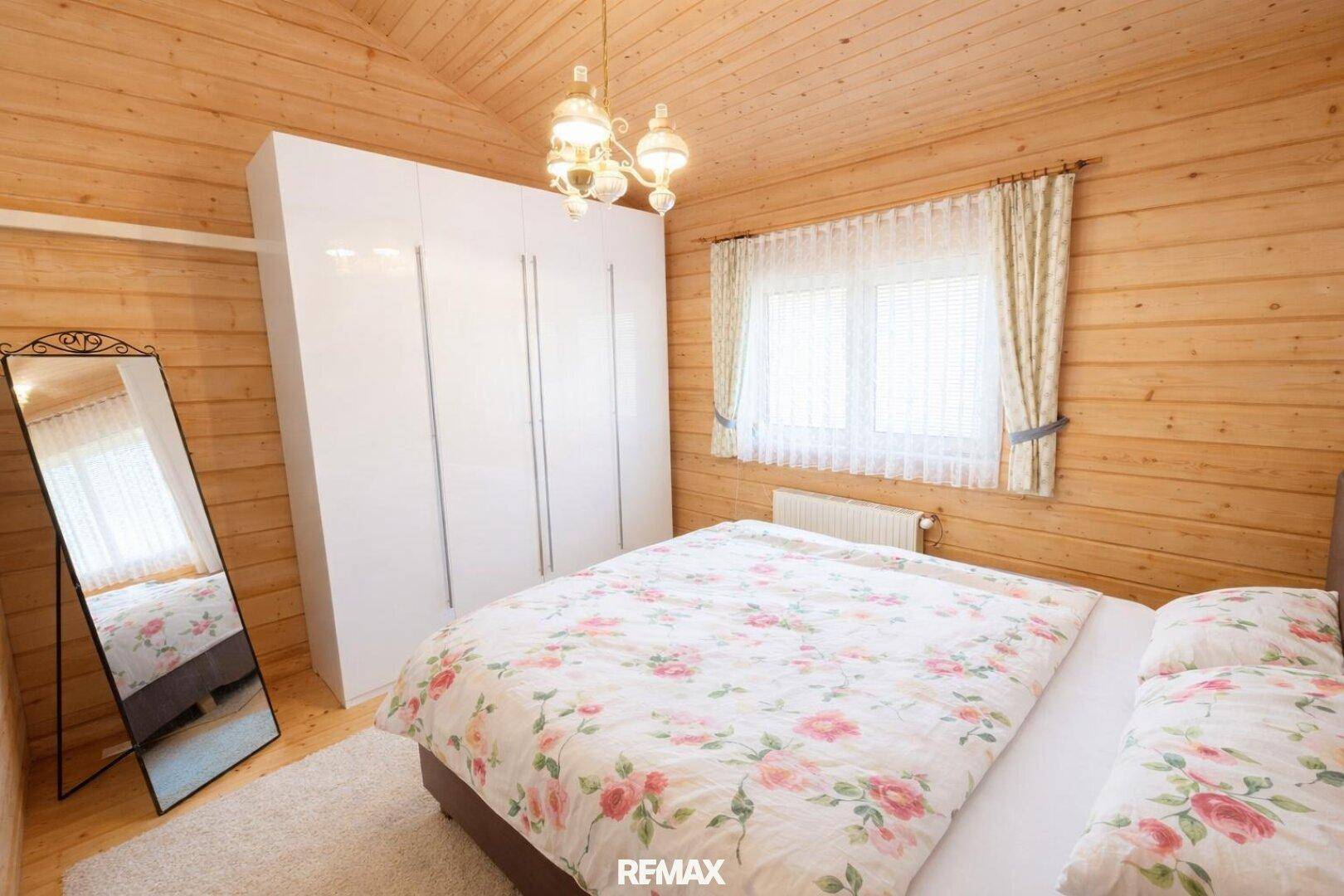 Gemütliches Schlafzimmer mit Holzvertäfelung, großem Bett und weißem Kleiderschrank.