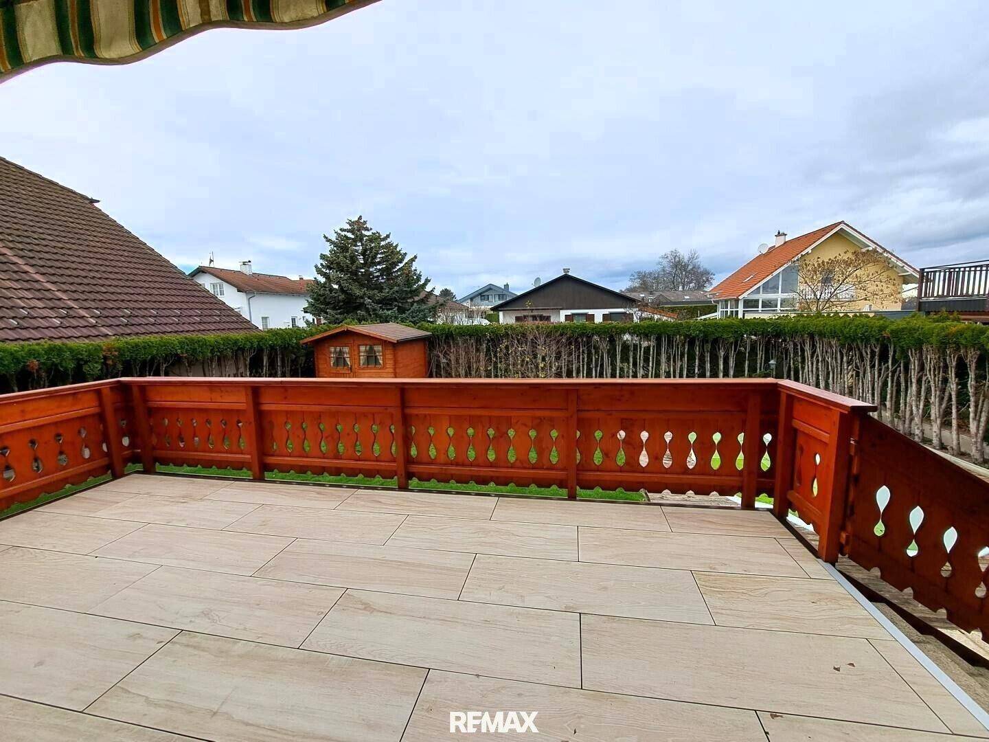 Geräumige Terrasse mit Holzbalkonbrüstung und Blick auf den Garten und die Umgebung.