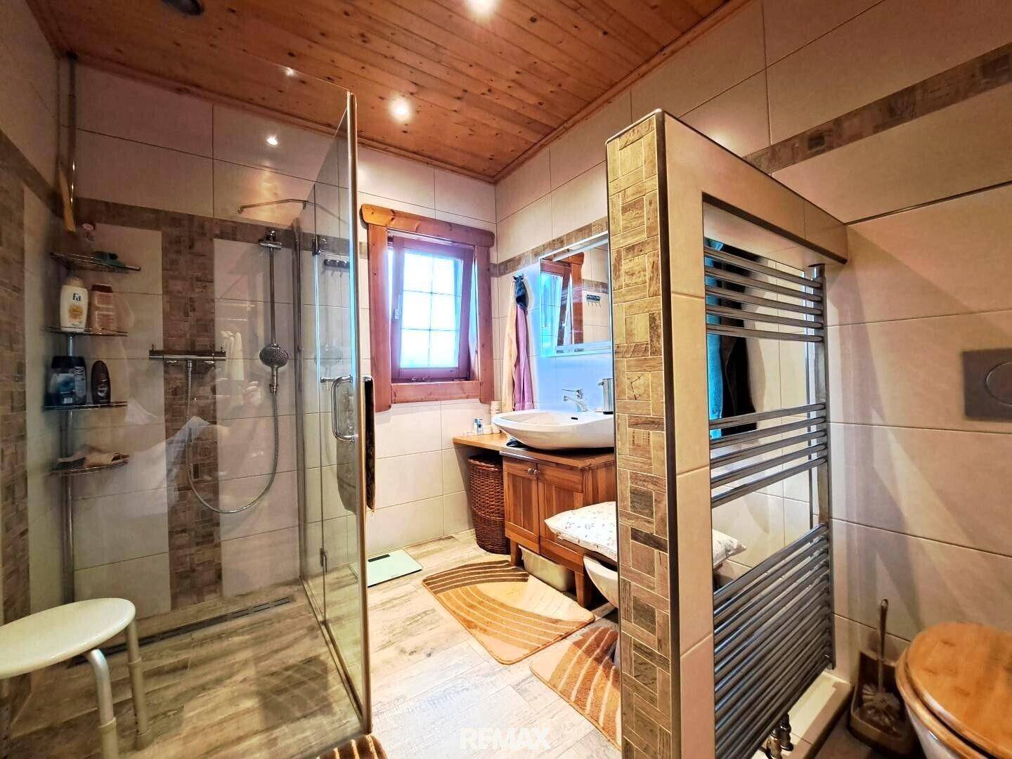 Modernes Badezimmer mit begehbarer Dusche, Holzdecke und beheiztem Handtuchhalter.