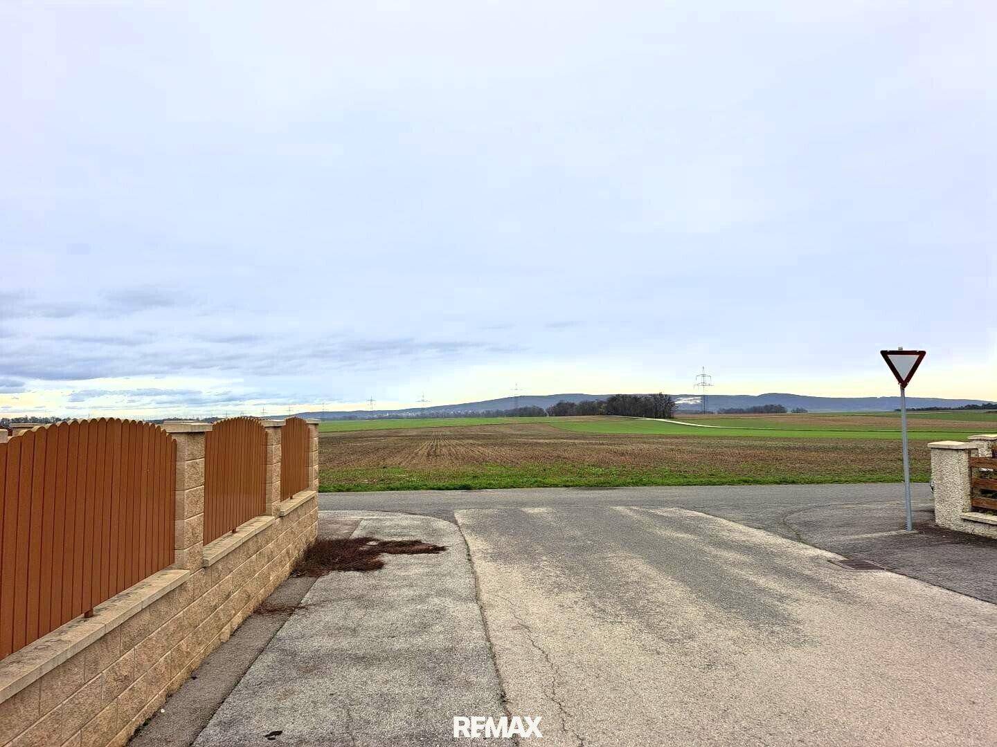 Weitläufiger Blick über die ländliche Umgebung mit Feldern und bewölktem Himmel.