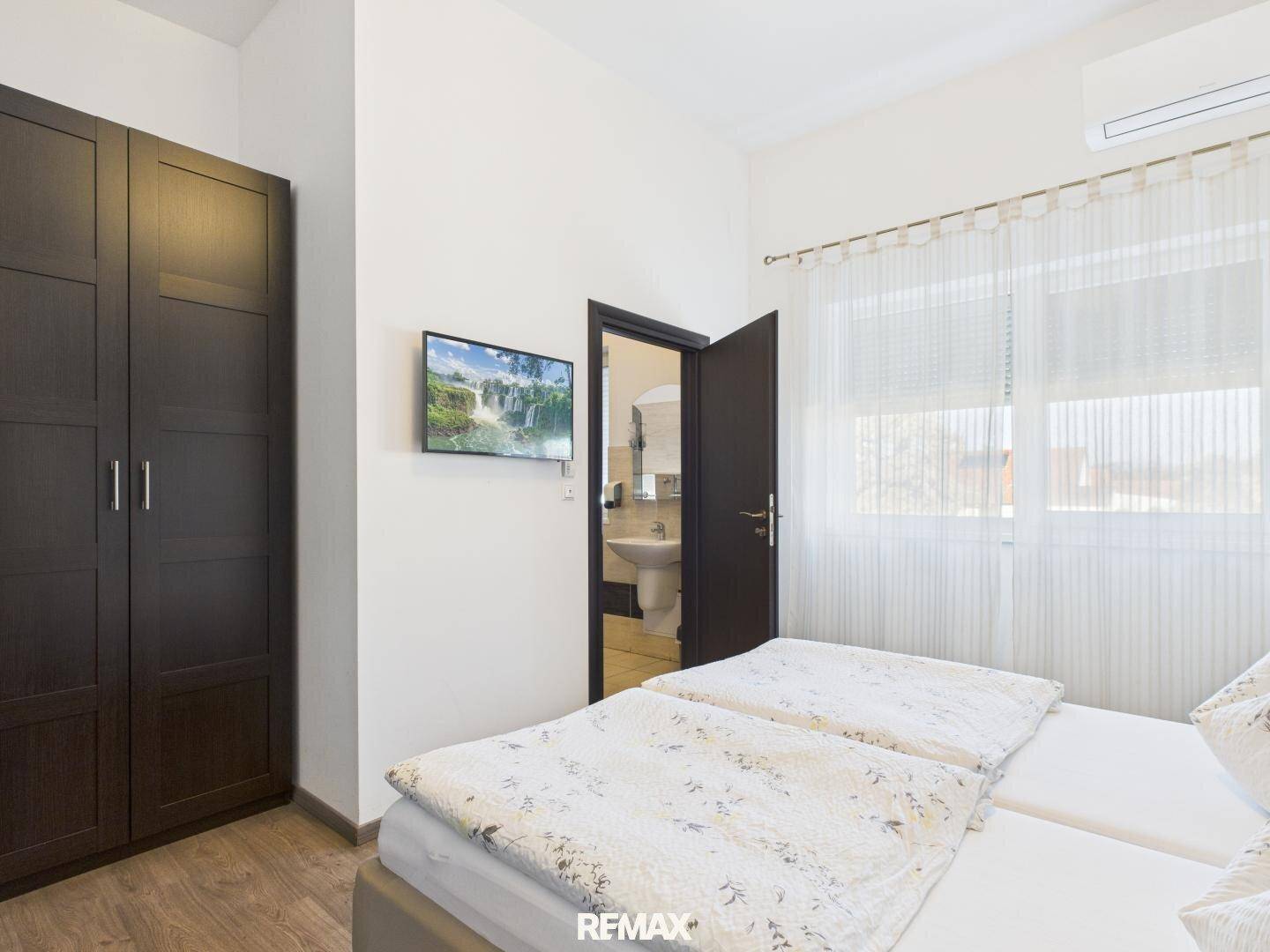 Schlafzimmer mit zwei Einzelbetten, einem Kleiderschrank und Zugang zu einem angrenzenden Badezimmer.