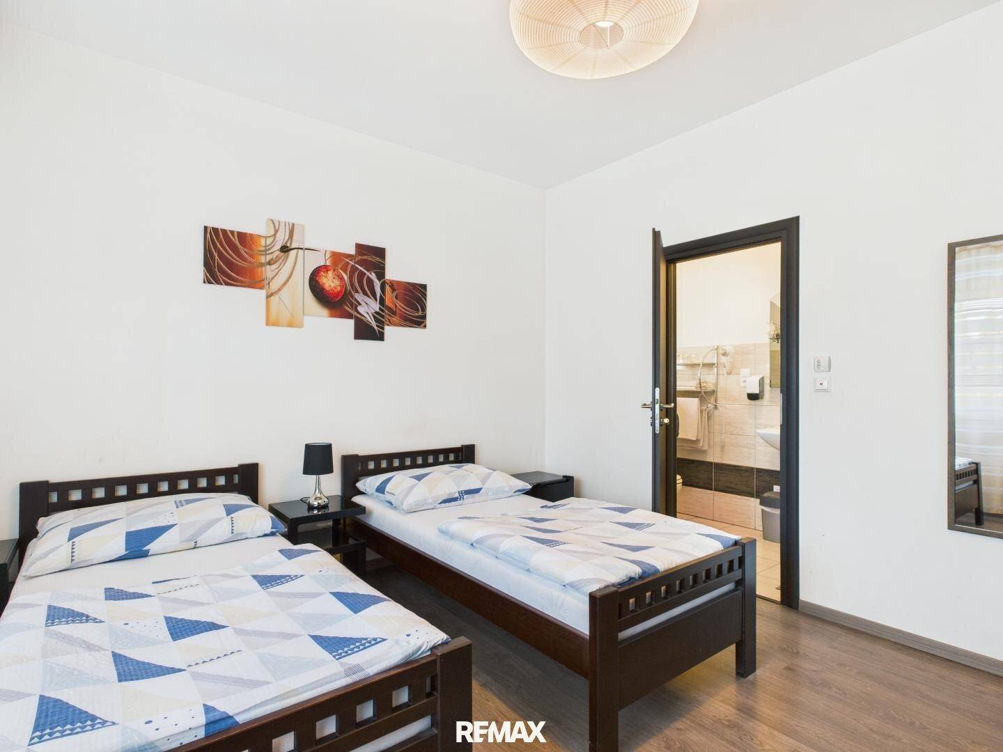 Schlafzimmer mit zwei Einzelbetten und Zugang zu einem Badezimmer, dekoriert mit einem modernen Wandbild.
