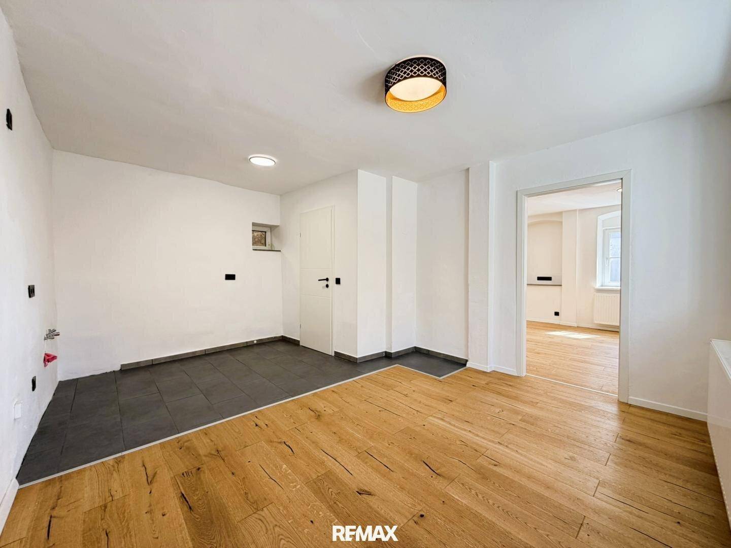 Geräumiger Raum mit gemischtem Bodenbelag aus Fliesen und Holz, ideal für flexible Nutzung.
