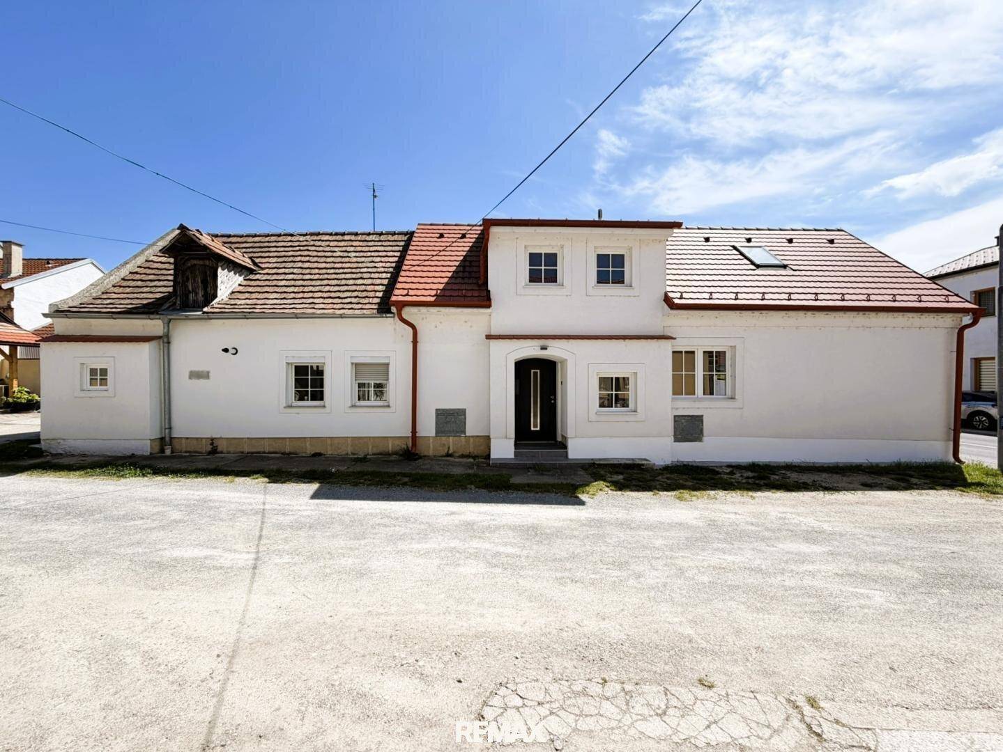 Gesamtansicht des weißen Hauses mit rotem Ziegeldach und Eingangsbereich von vorne.