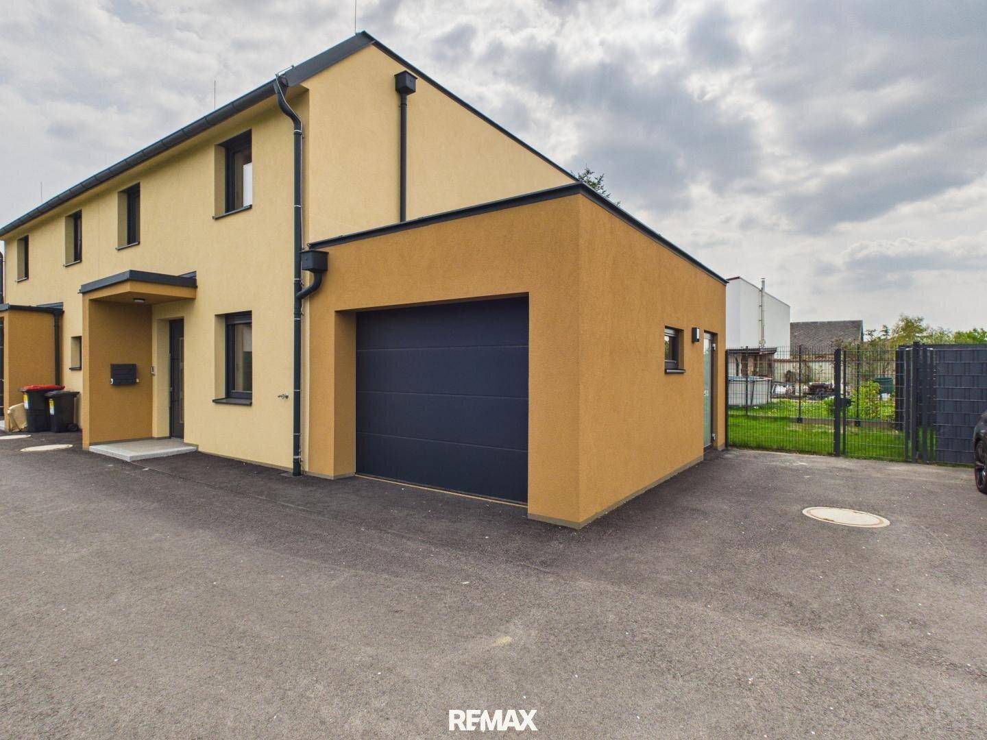 Außenansicht des modernen Reihenhauses mit integrierter Garage und dunklem Tor.