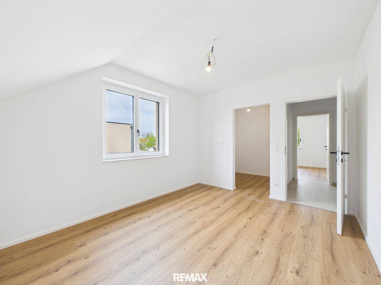Geräumiges Zimmer im Dachgeschoss mit Holzboden und Zugang zu weiteren Räumen.