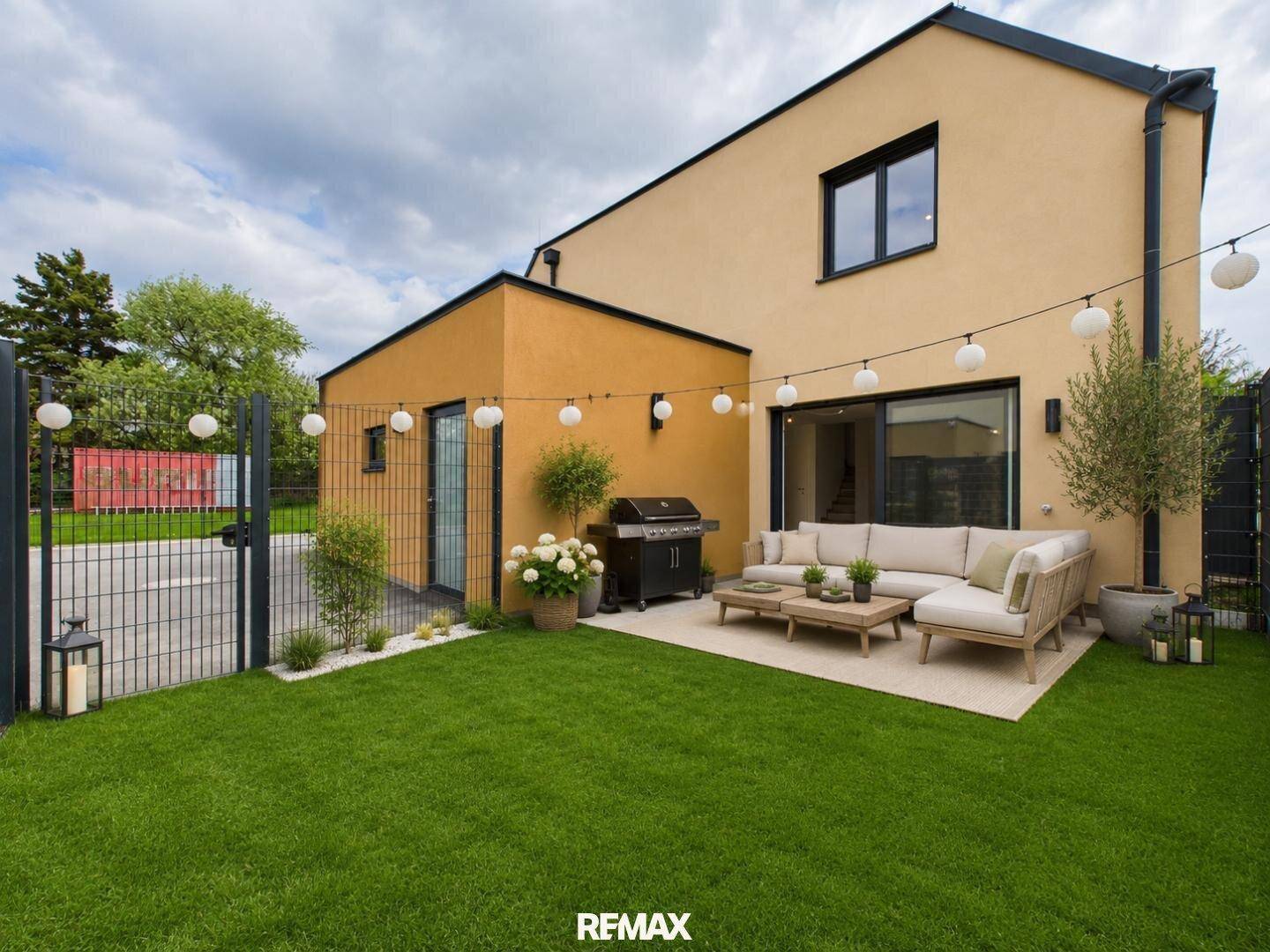 Möblierte Terrasse mit Rasenfläche, Grill und dekorativer Beleuchtung am modernen Haus.