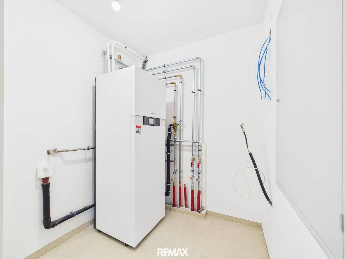 Technikraum mit moderner Heizungsanlage und sichtbaren Rohrleitungen.