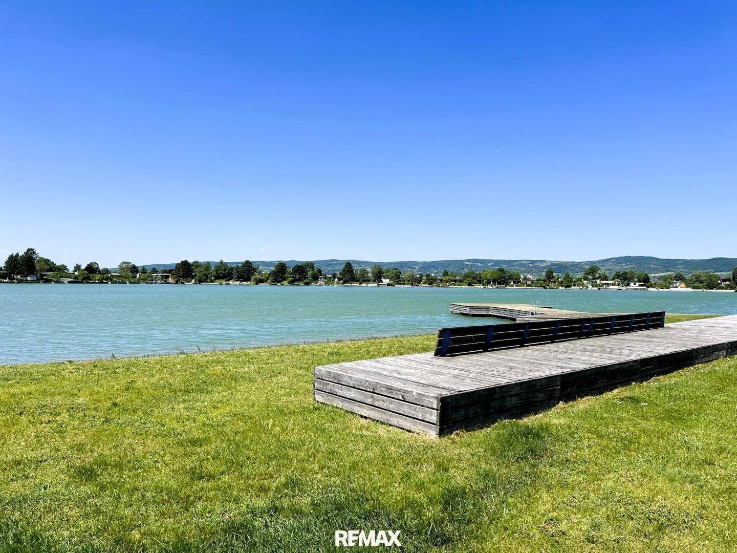 Malerischer Blick auf einen See mit grünen Ufern und blauem Himmel.