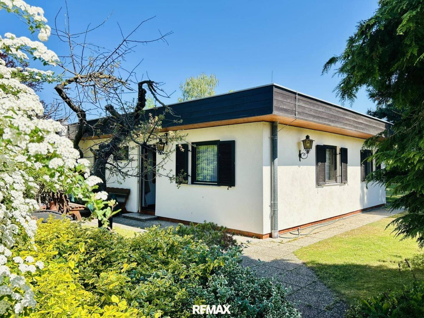 Vorderansicht des Hauses umgeben von blühenden Sträuchern und einem gepflegten Gartenweg.