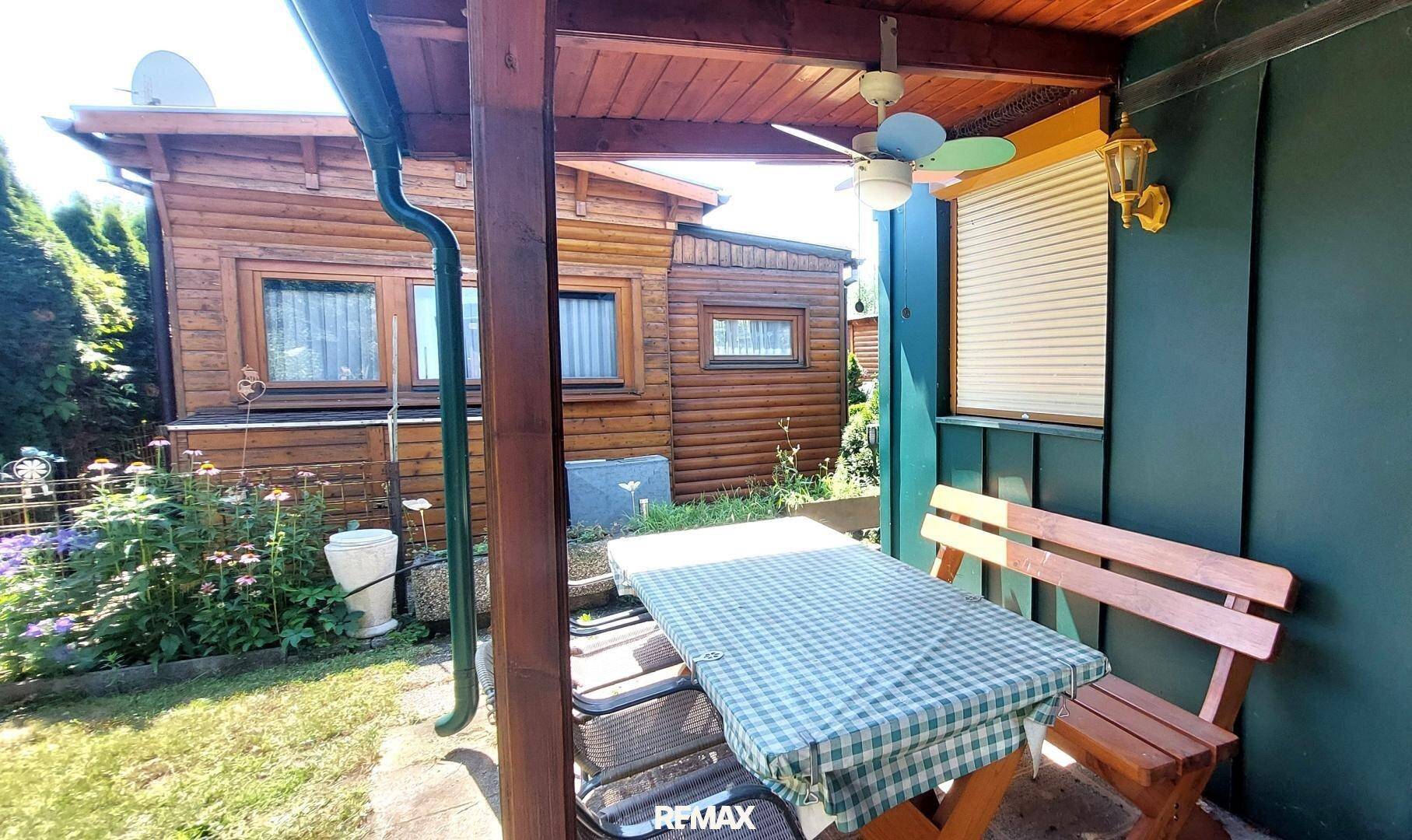 Gemütliche überdachte Terrasse mit Esstisch, Sitzbank und Deckenventilator für angenehme Stunden im Freien.