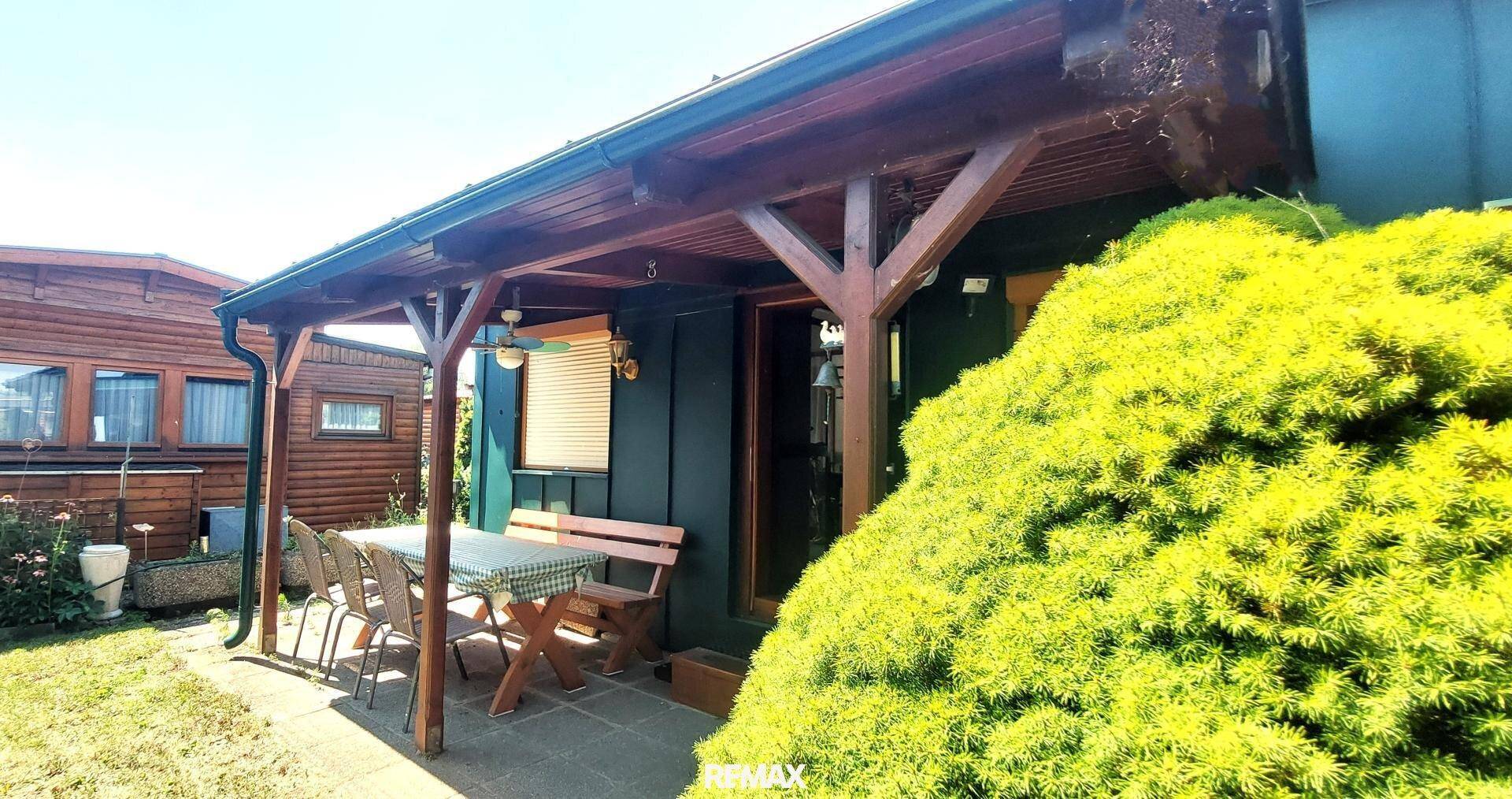 Überdachte Terrasse mit Holztisch und Sitzbank, ideal für Mahlzeiten im Freien und Entspannung.