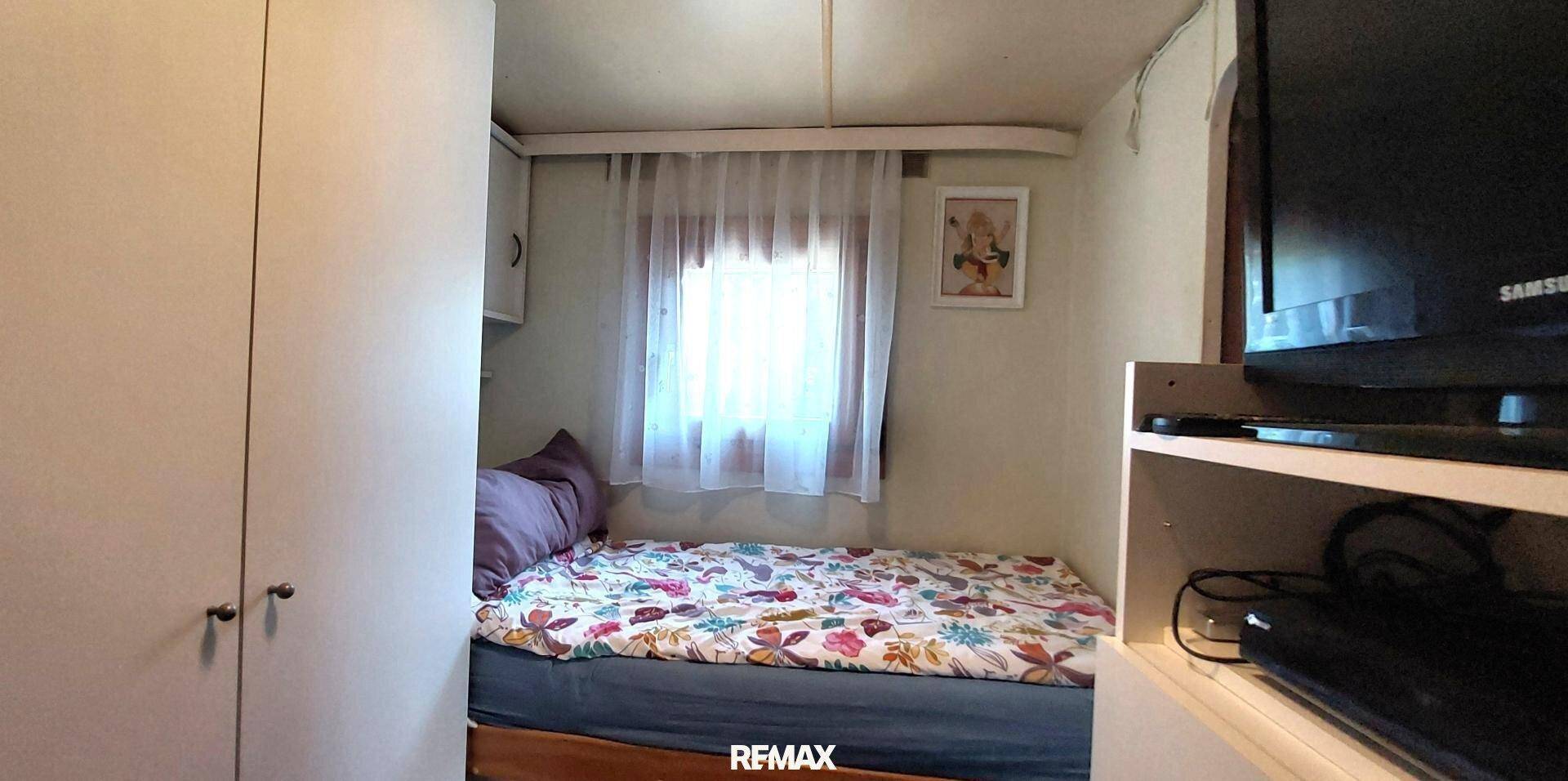 Kleines Schlafzimmer mit Einzelbett, weißem Schrank und einem Fenster, das für natürliche Belichtung sorgt.