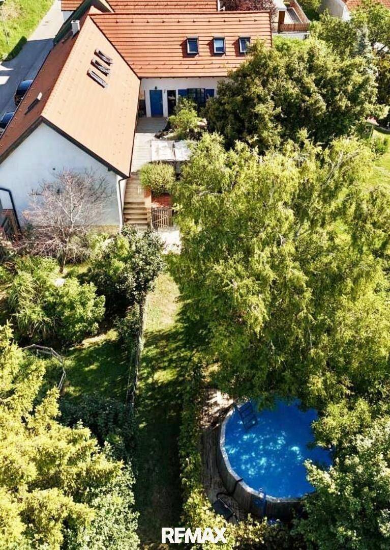 Luftaufnahme des Anwesens mit Haus, großem Garten und einem oberirdischen Swimmingpool.