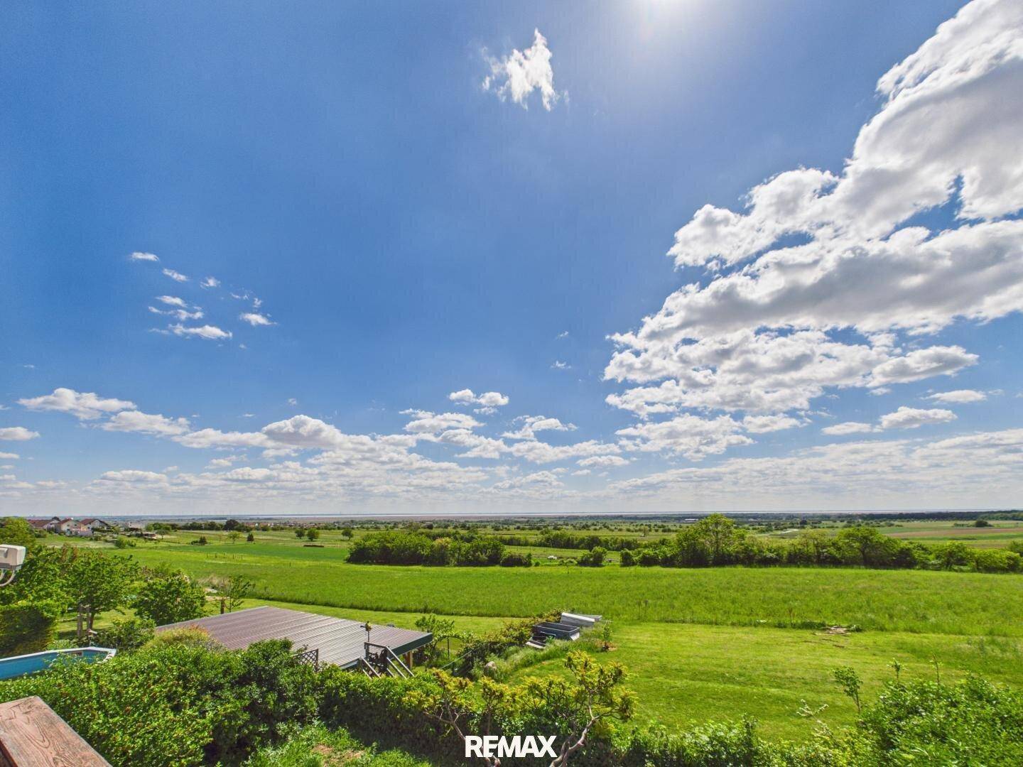 Weitläufiger Blick über grüne Felder und die Landschaft unter einem strahlend blauen Himmel.