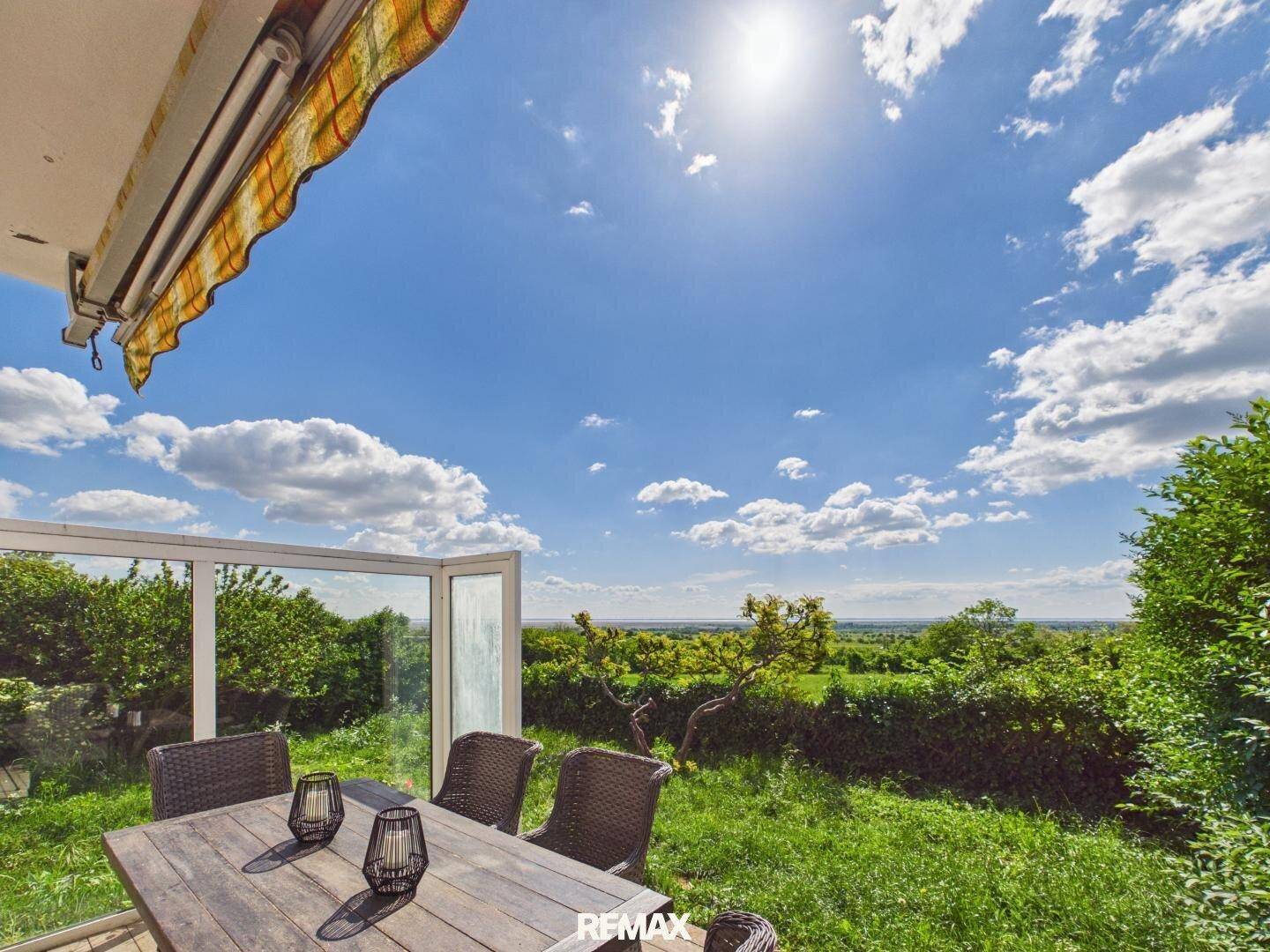 Sonnenterrasse mit Esstisch und weitem Blick über die grüne Landschaft.