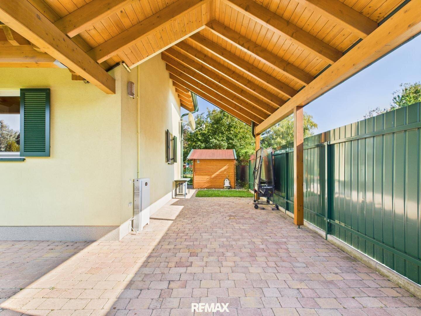 Langer Carport-Bereich mit Holzdach und Zugang zum Garten.
