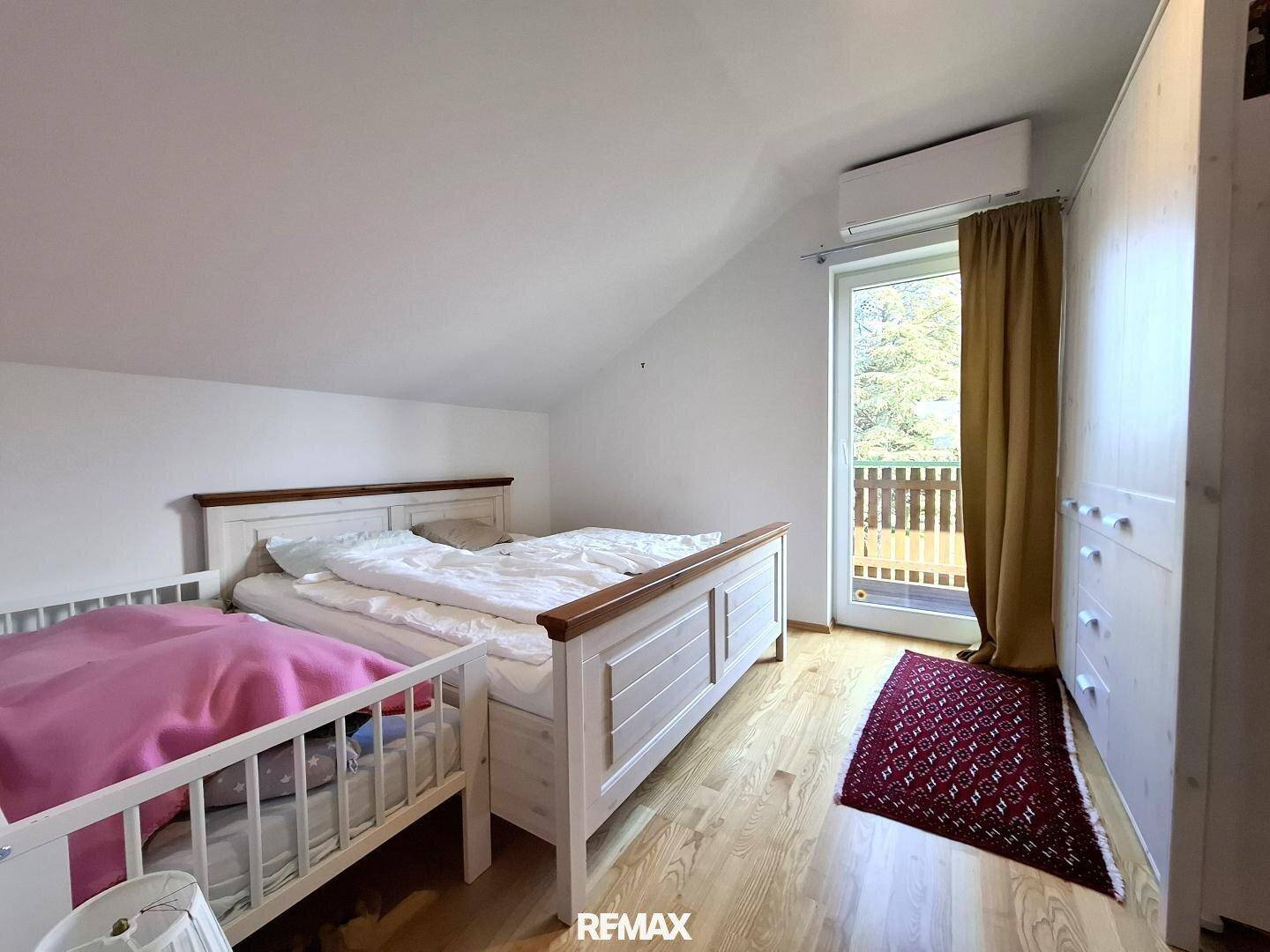 Schlafzimmer im Dachgeschoss mit Holzboden und Zugang zum Balkon.
