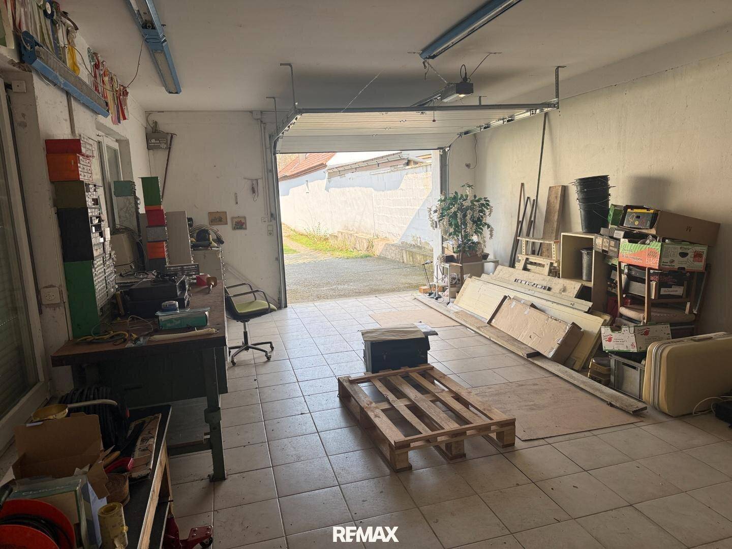 Geräumige Garage oder Werkstatt mit offenem Tor und viel Stauraum.