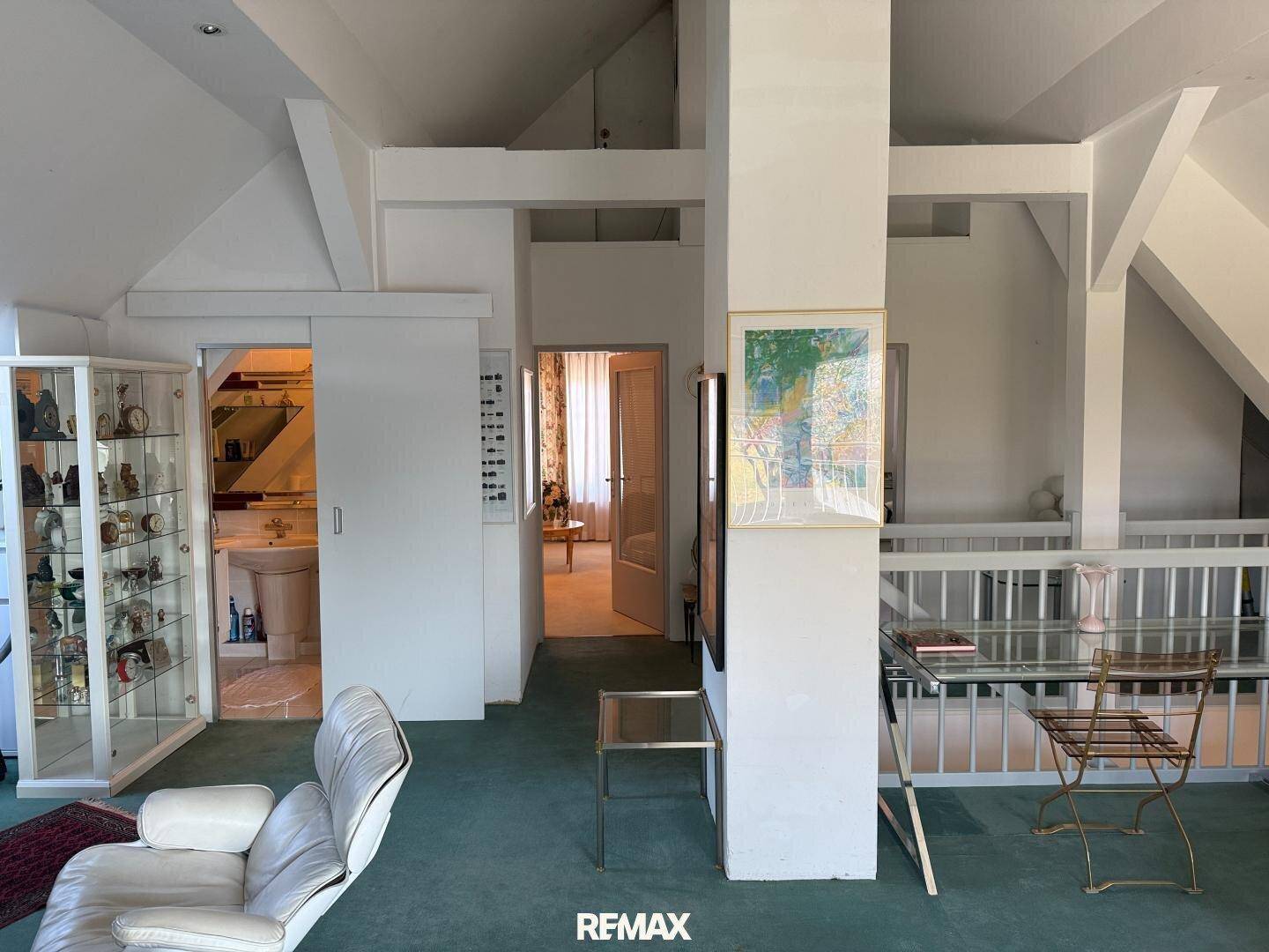 Offener Wohnbereich im Dachgeschoss mit Blick auf einen angrenzenden Badezimmerbereich.
