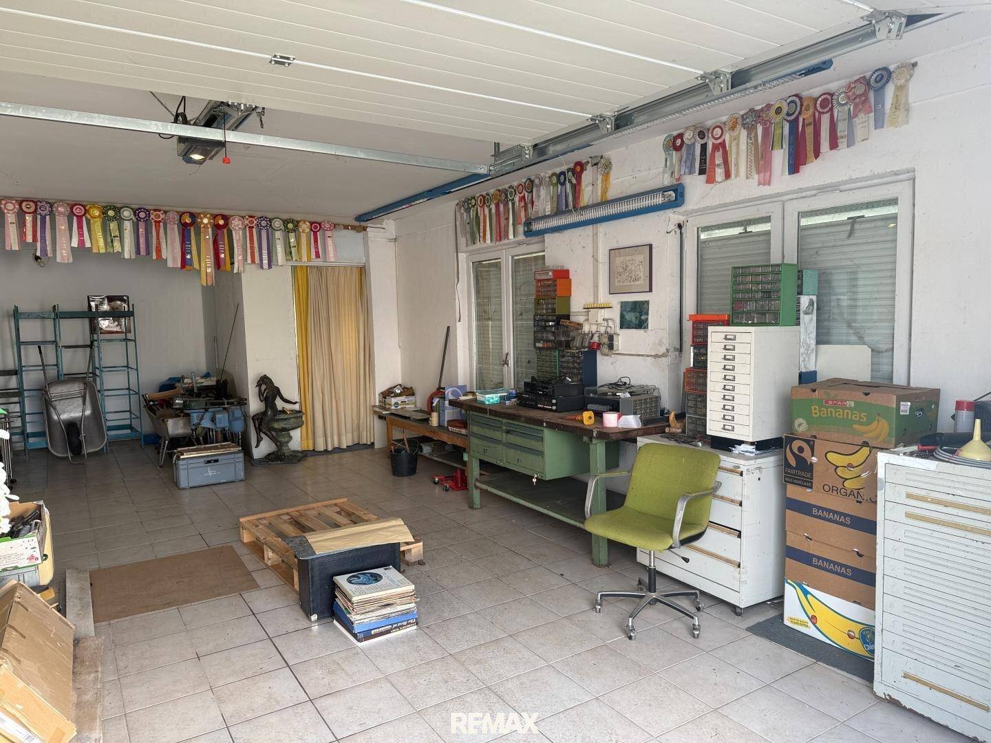 Innenansicht der Garage mit Fliesenboden, Werkbank und verschiedenen Utensilien.