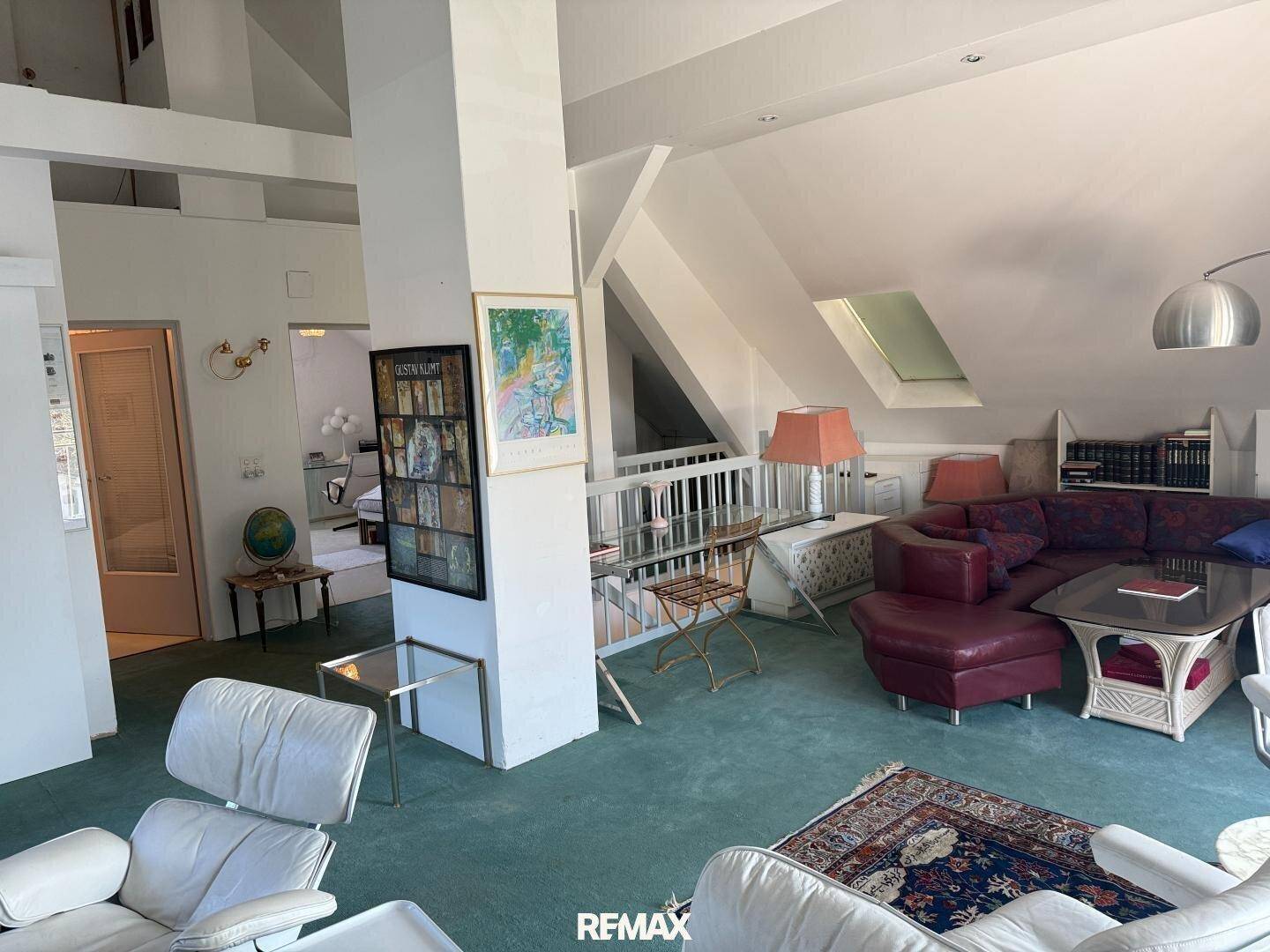 Geräumiges Wohnzimmer im Dachgeschoss mit Teppichboden, Dachfenstern und gemütlicher Sitzecke.
