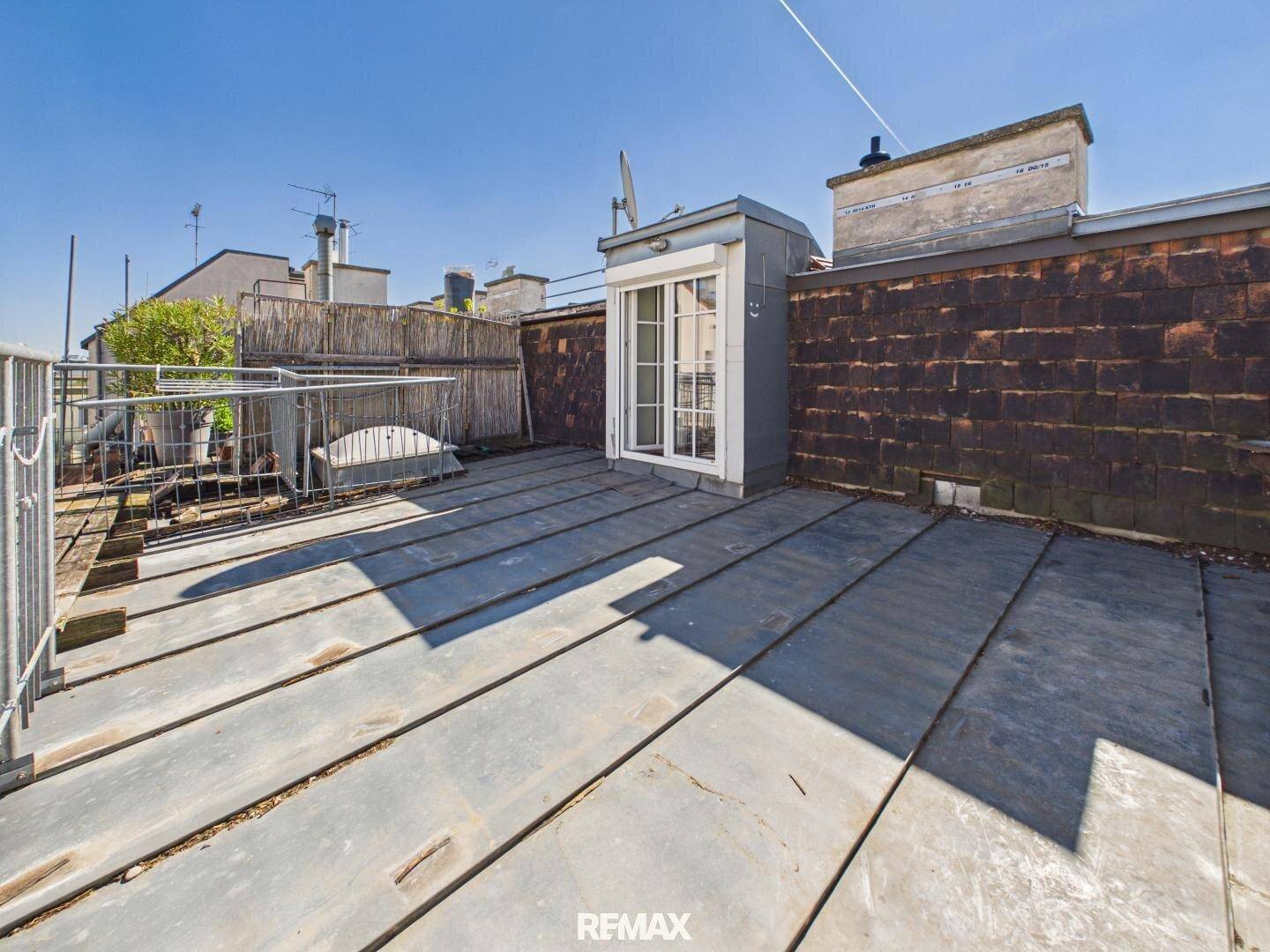 Dachterrasse mit Metallplattenboden, Pflanzen und Zugang zum Innenbereich.